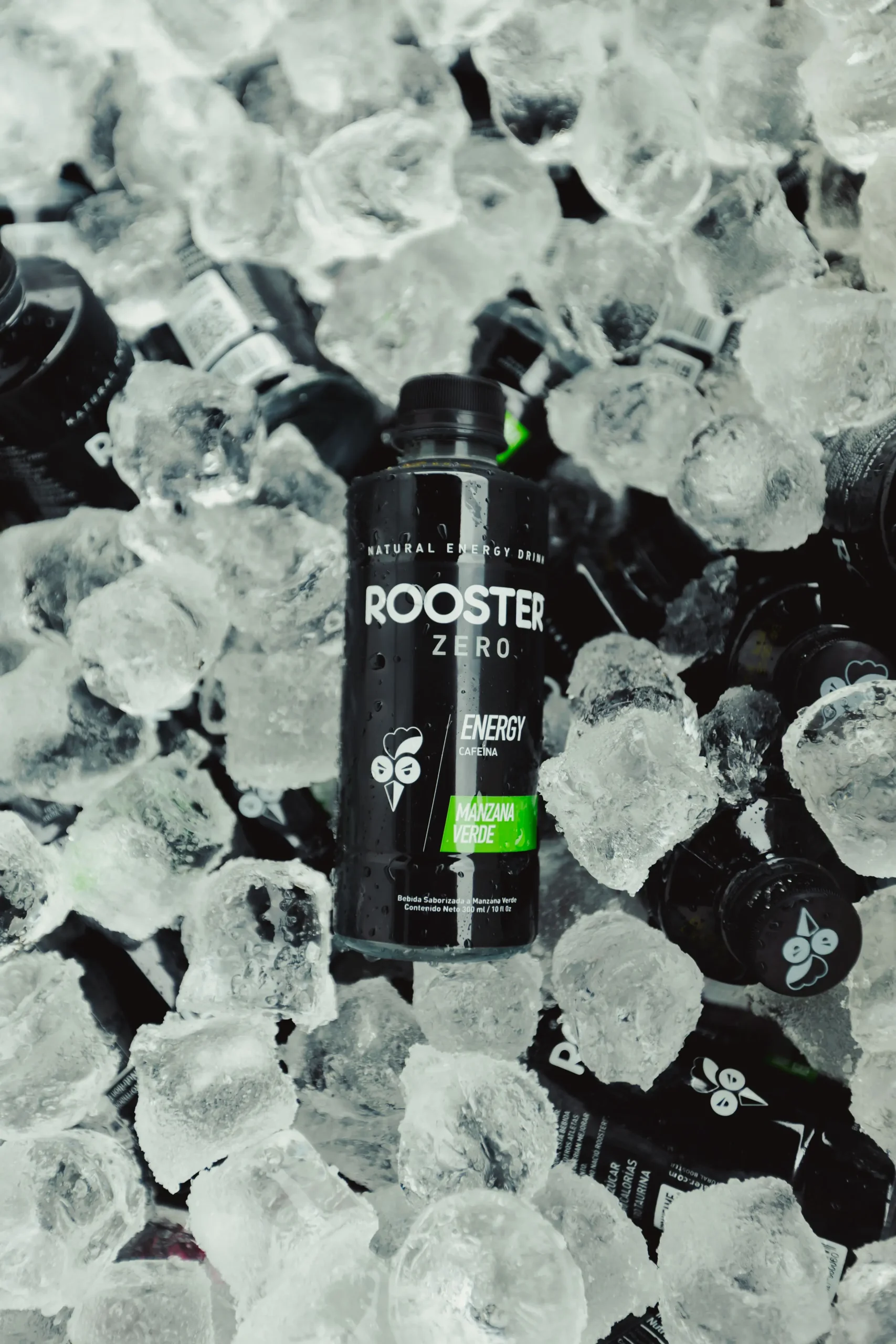 A bottle of Rooster Zero green apple energy drink resting on ice