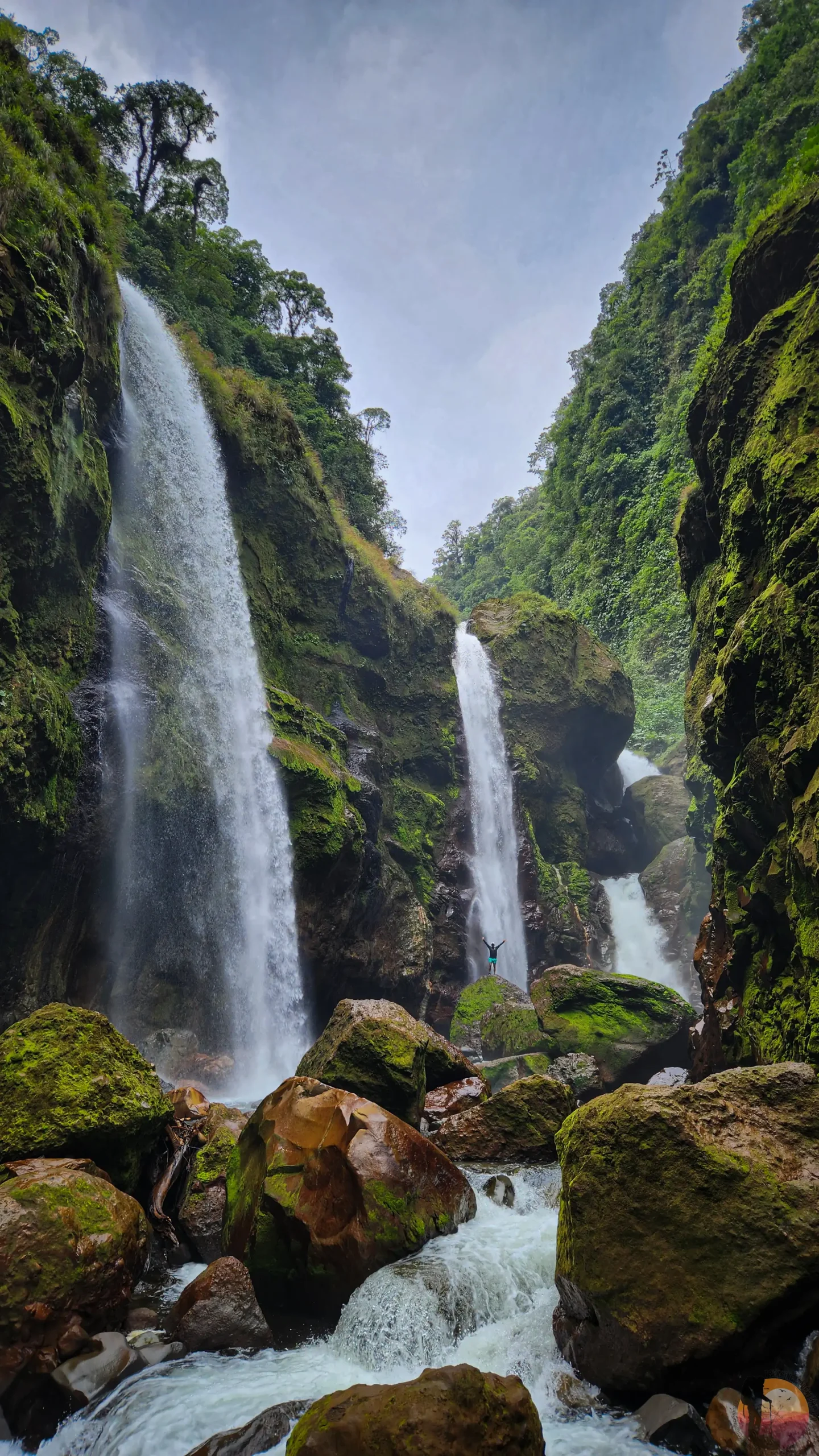 Hiker below a tall waterfall on the Quebrada Gata route
